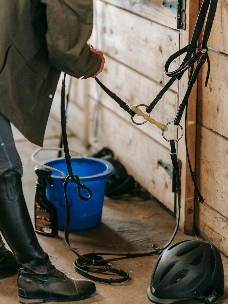 Stable Supplies -Person holding bridle/reins inside of a barn